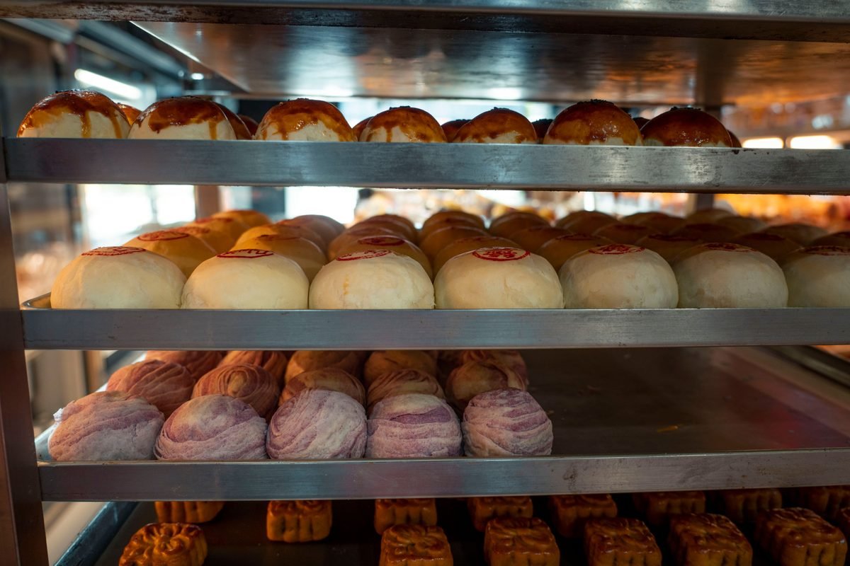 Assorted traditional Asian sweet and red bean buns displayed on bakery shelves