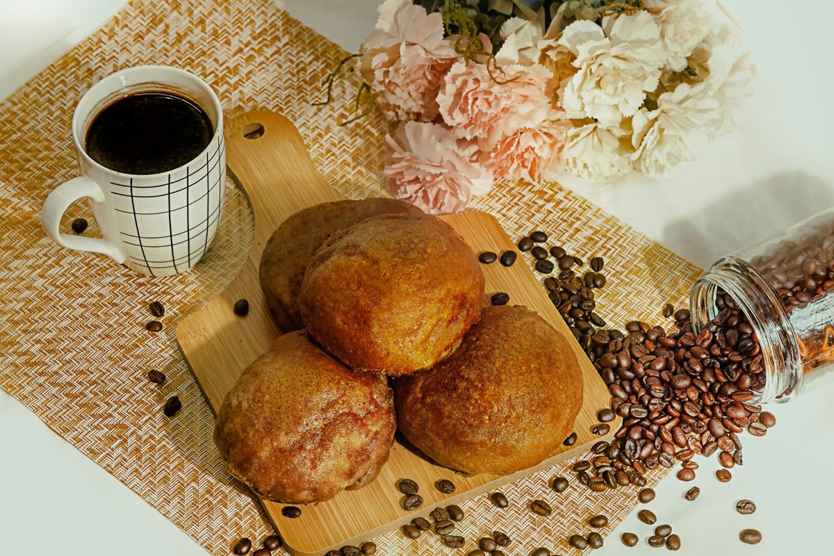 Warm golden pastries on a wooden board next to a cup of coffee