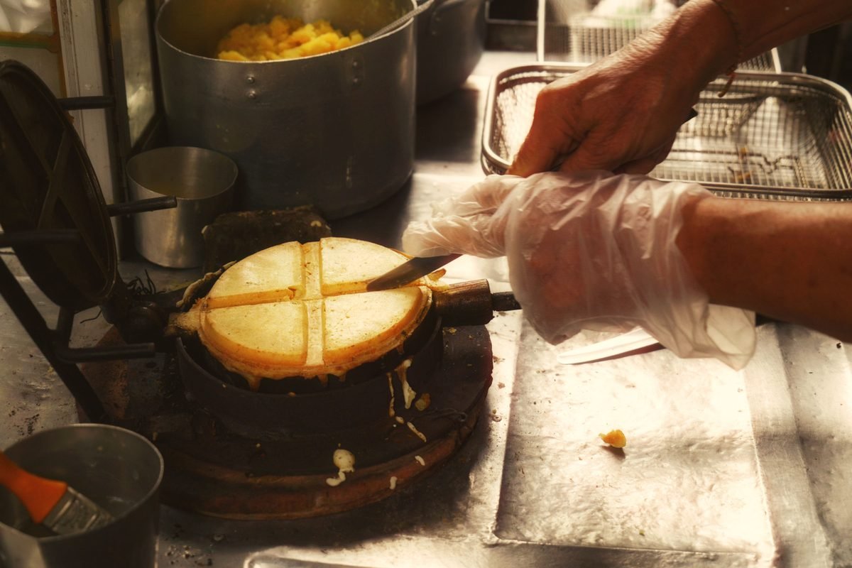 Street vendor preparing round street snacks in a traditional iron mold
