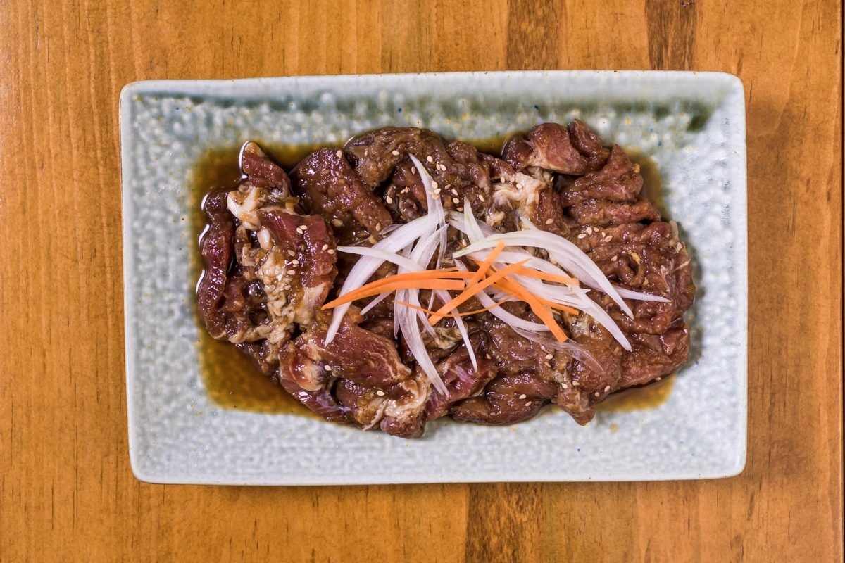 Close-up of marinated Korean beef bulgogi with sliced onions and carrots on a plate