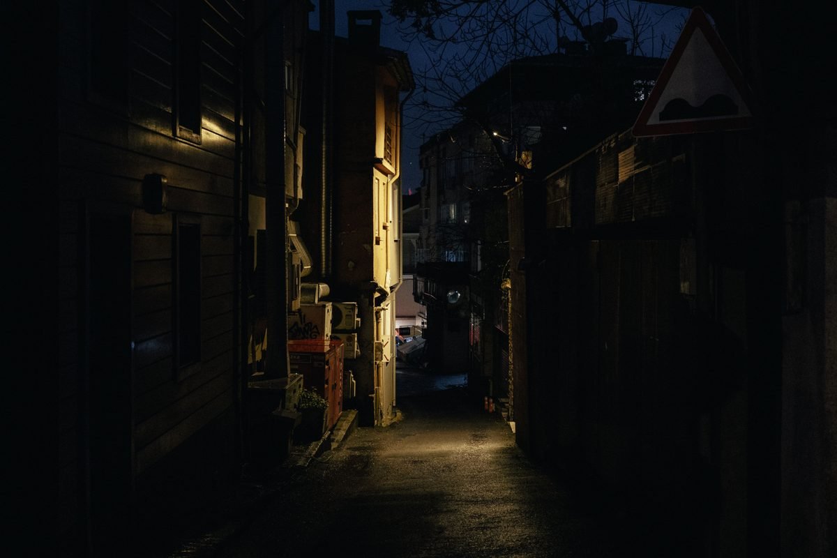 Dimly lit narrow alleyway at night with urban architecture