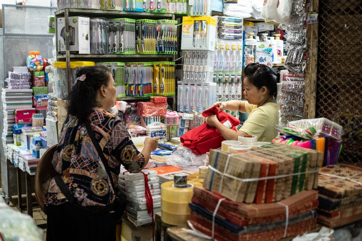 Stalls stacked with goods and shopkeepers inside a busy market in Hanoi