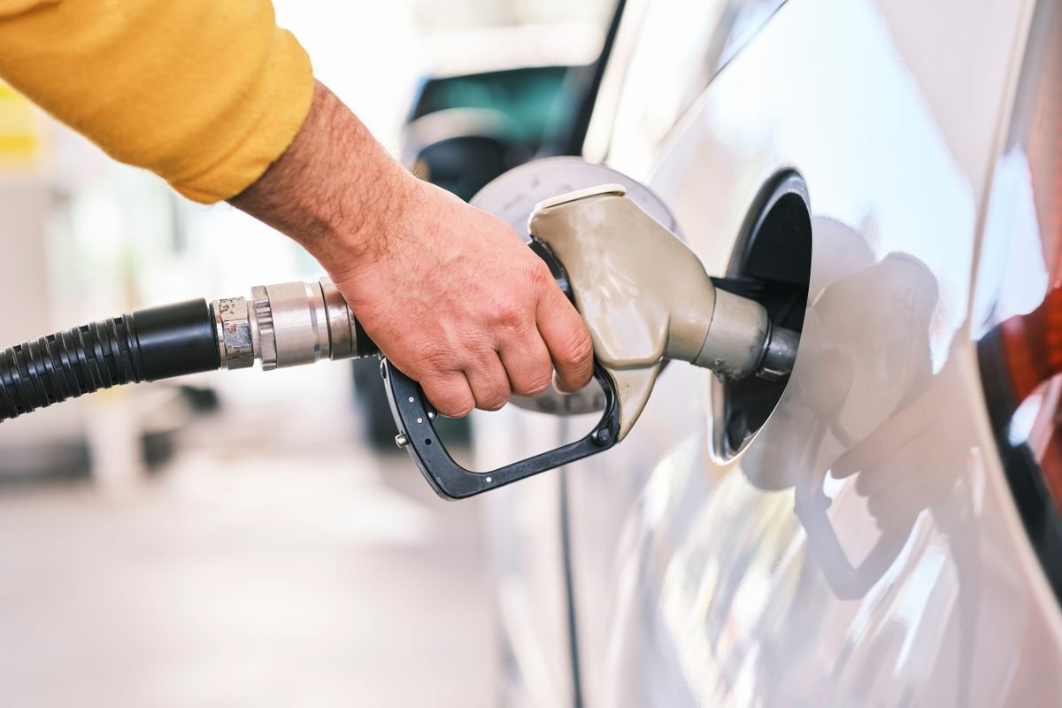 Close-up of a person refueling a car with a gas nozzle at a station.