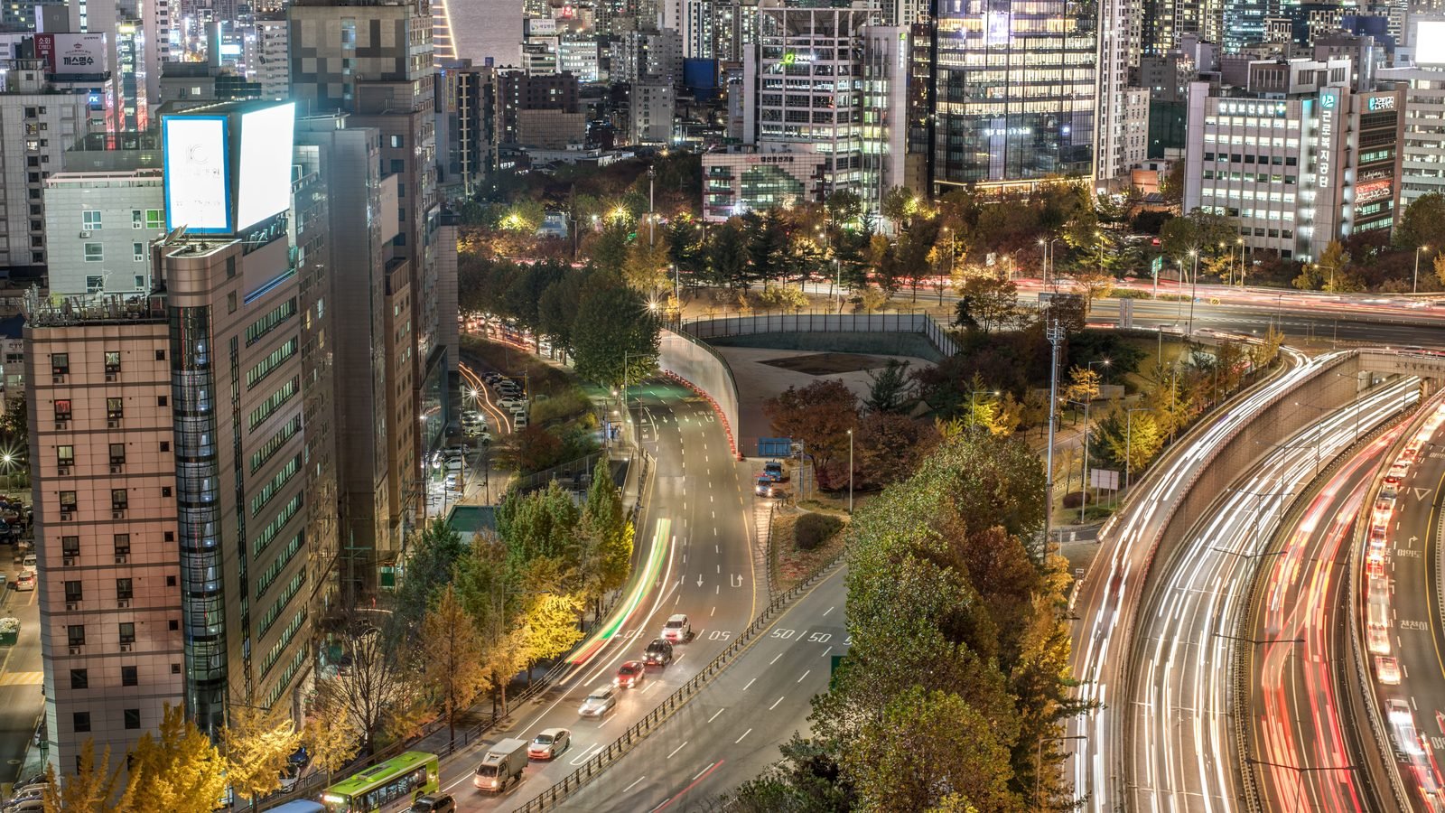 A bustling Seoul street with illuminated buildings and traffic at night.