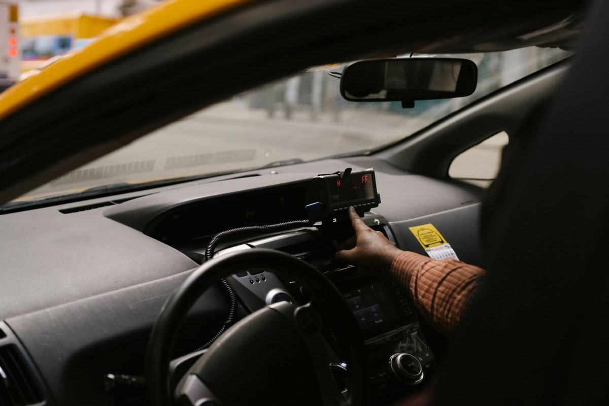 Driver interacting with dashboard equipment inside a taxi.