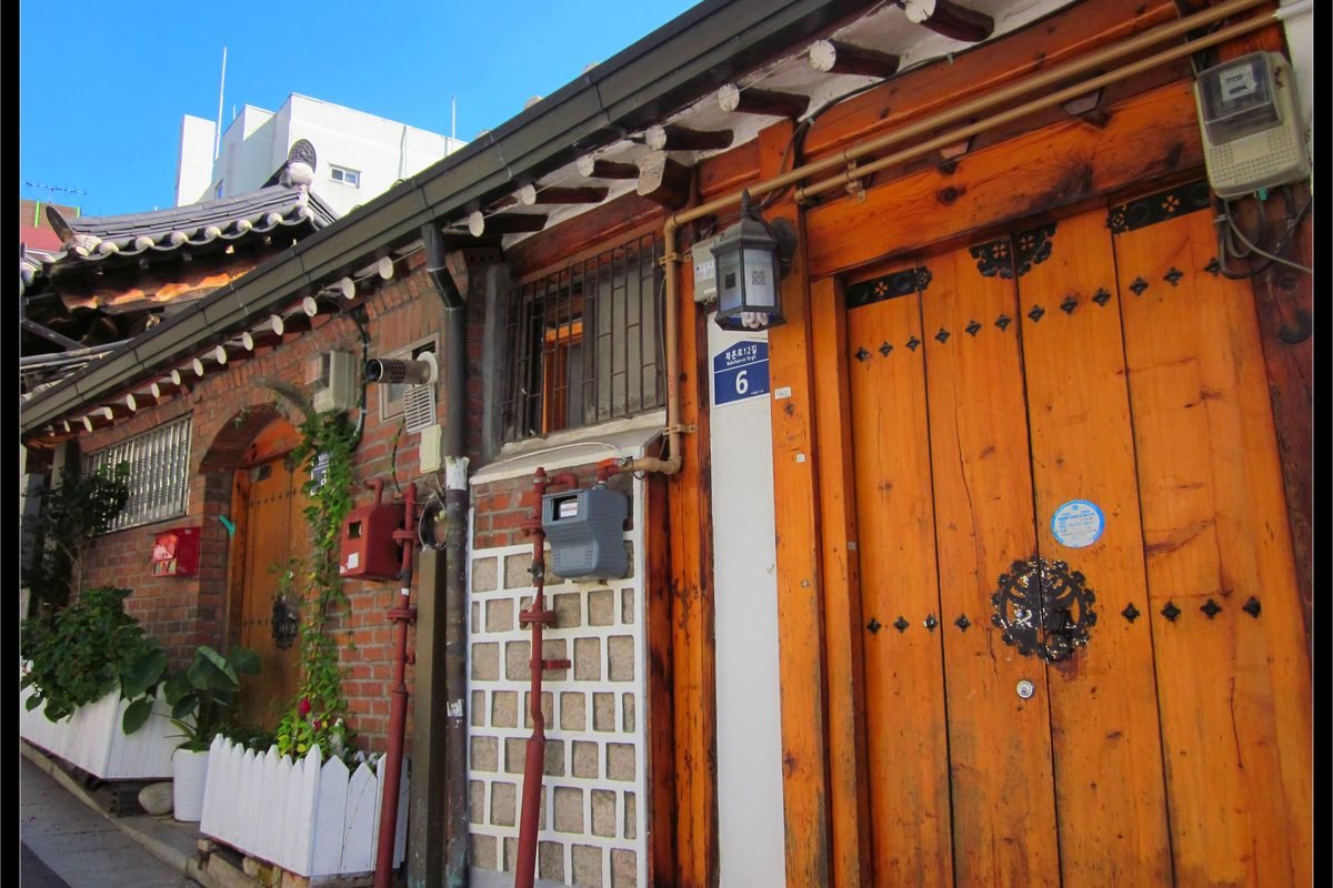 Traditional wooden door and brick wall of a Hanok in Seoul.