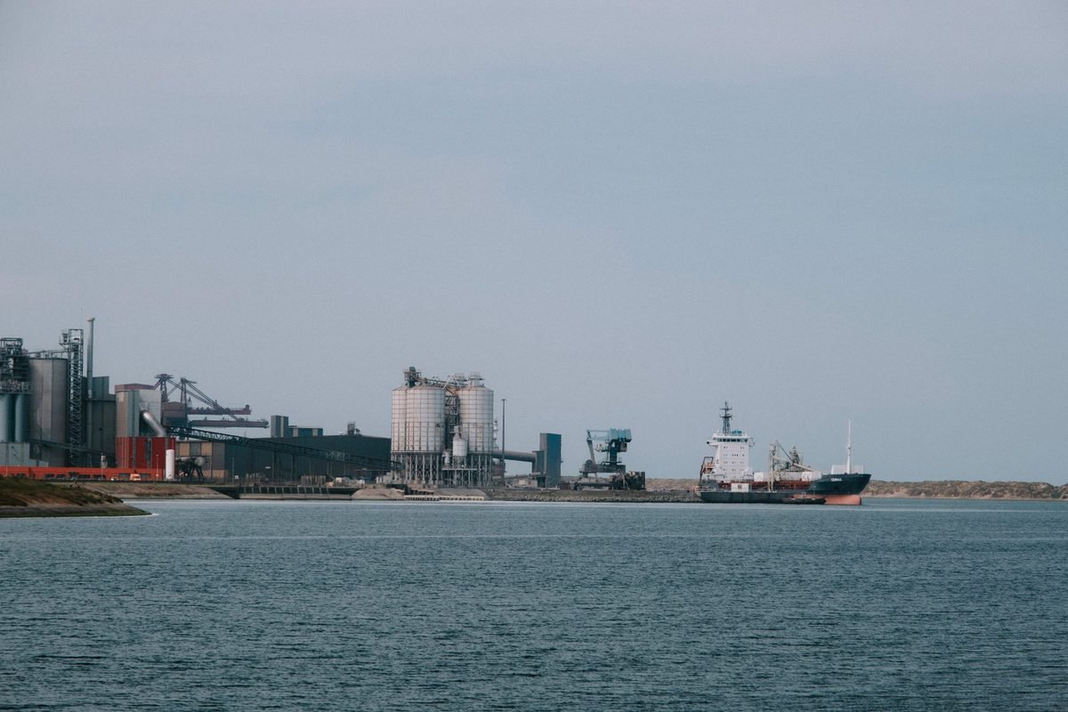 Cargo ship docked at an industrial port with silos