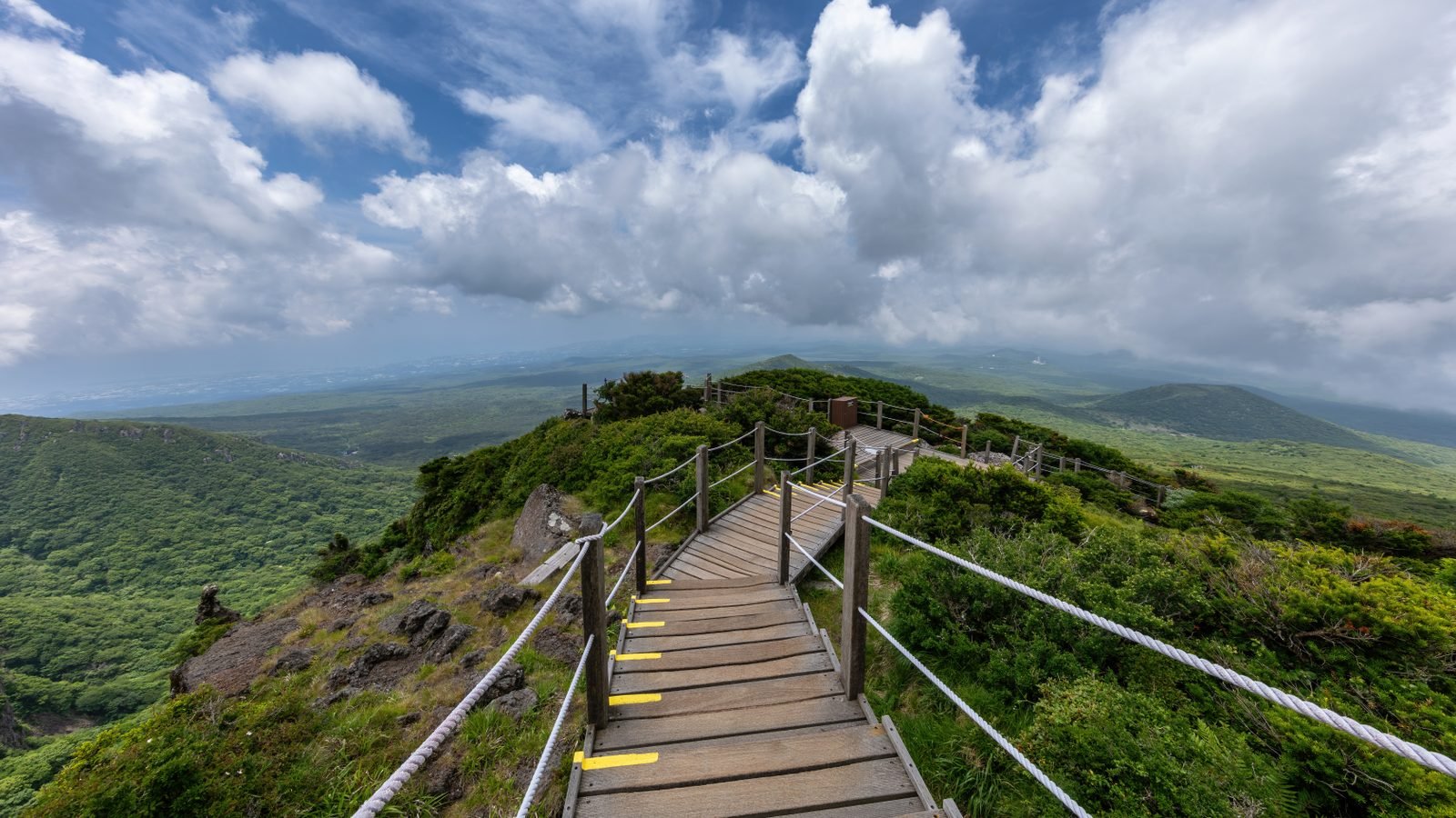 Wooden staircase along Yeongsil Trail overlooking green mountains in Hallasan Park Jeju Island South Korea.