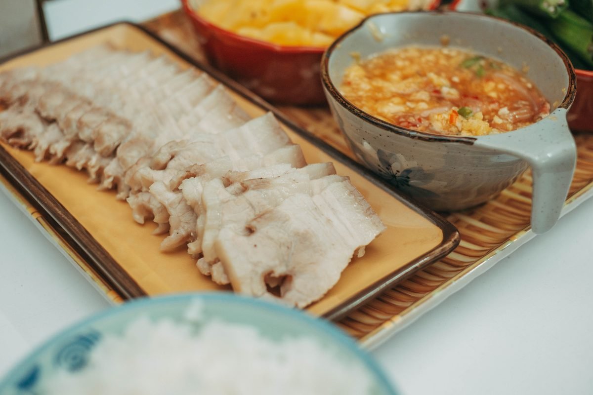 Sliced pork with dipping sauce on a dining table
