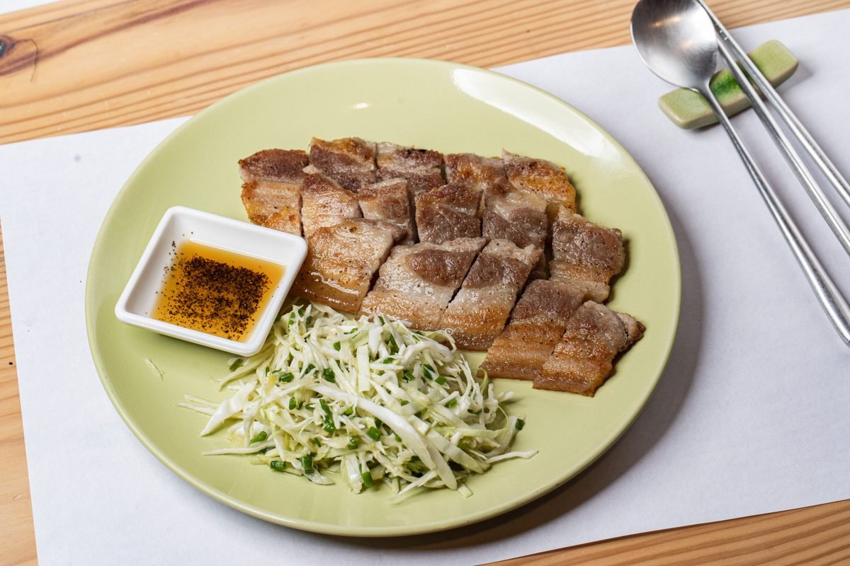 Grilled pork dish served with fresh cabbage and dipping sauce