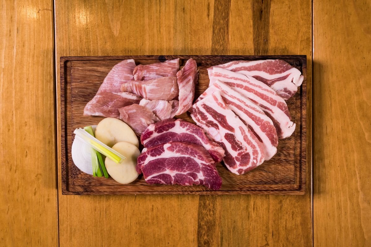 Assorted fresh cuts of pork presented on a rustic wooden board