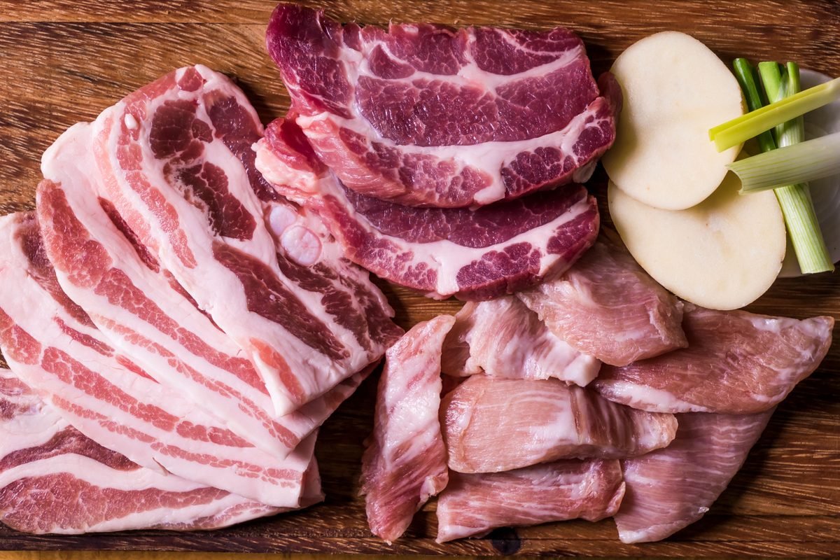 Close-up of raw pork belly slices on a wooden chopping board