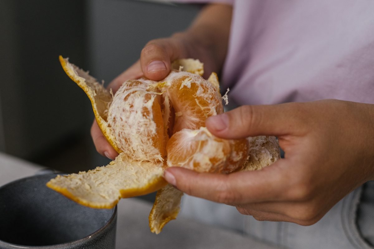 Close-up of hands peeling a fresh juicy orange