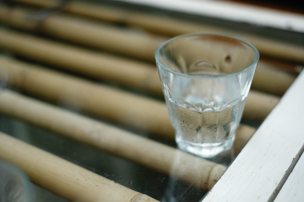 Shot glass with clear liquid placed on a bamboo surface