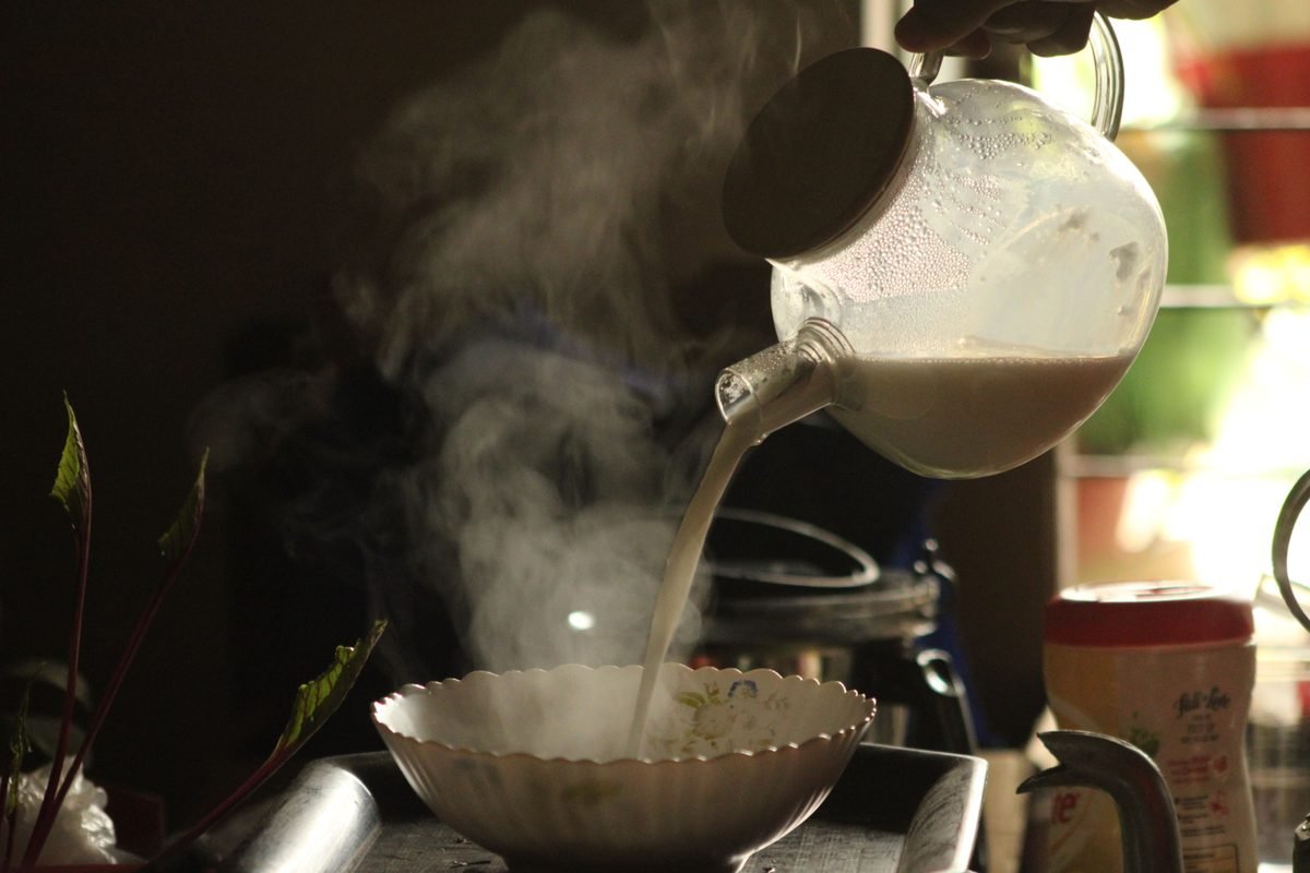 Warm light illuminating steaming milk being poured into a bowl