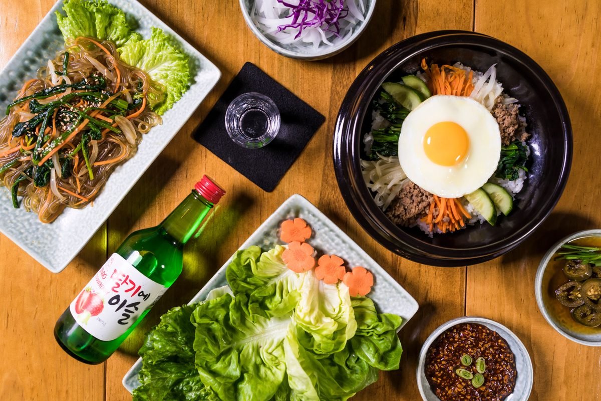 Top view of various Korean dishes including bibimbap and japchae