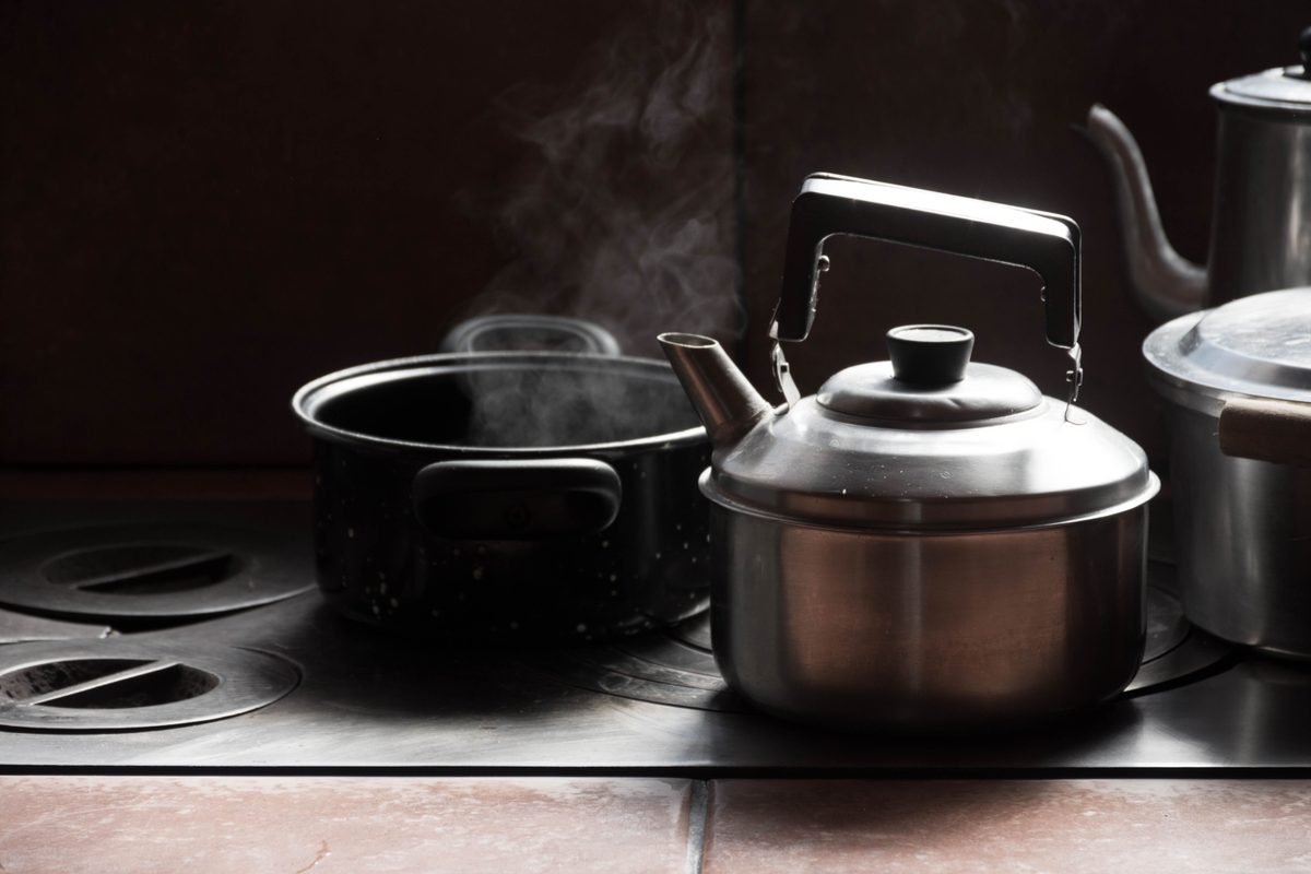 Steaming metal kettle and cooking pot on a stove