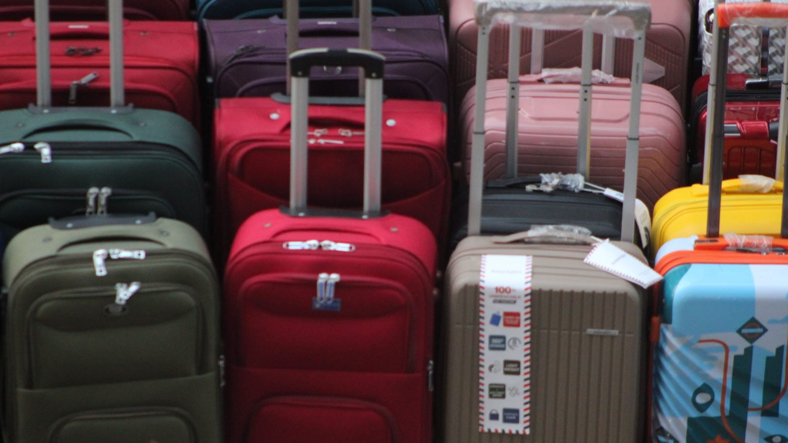 A vibrant collection of various suitcases stacked in preparation for travel