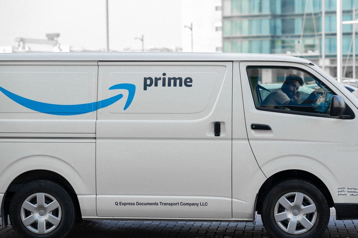 A white delivery van parked on an urban street with driver inside
