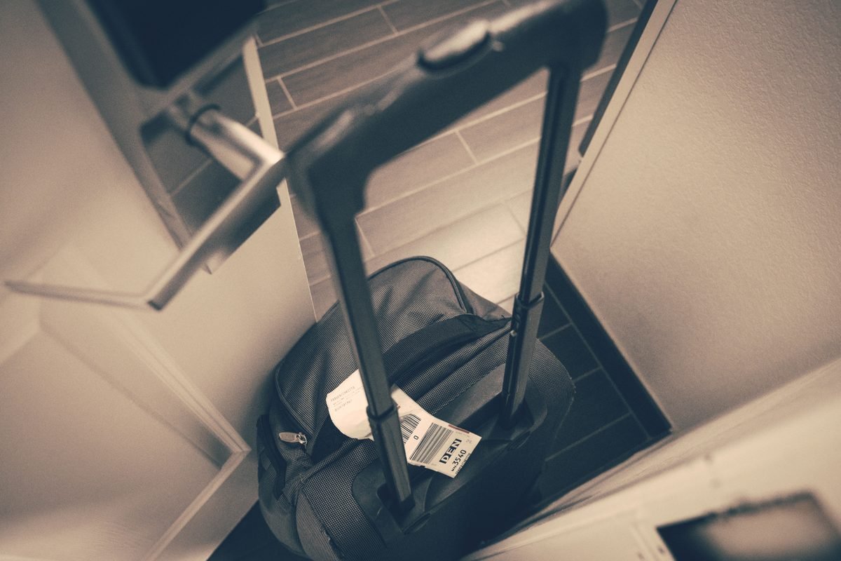 Travel suitcase with tag by hotel door symbolizing travel