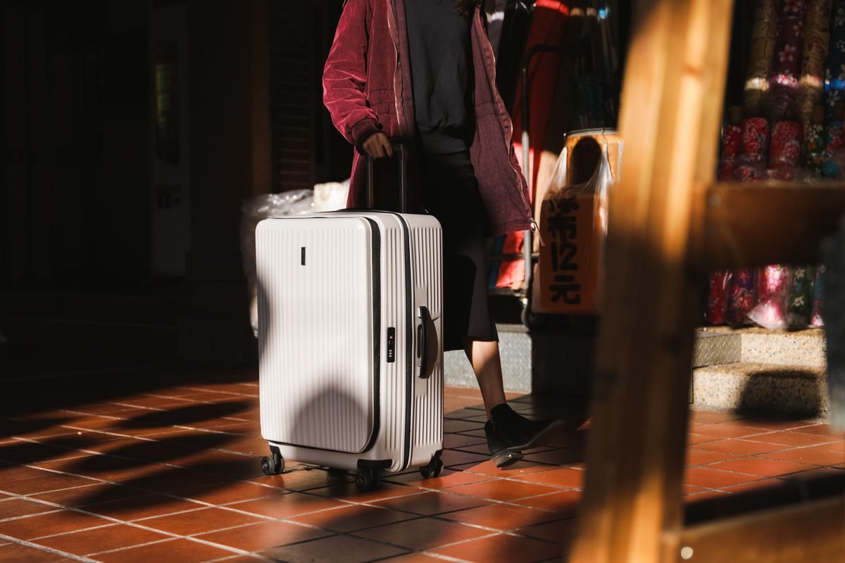 Woman walking with white suitcase in city street