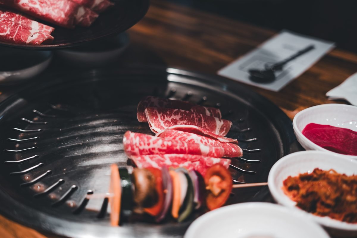 Korean BBQ table setting with sliced beef and side dishes.