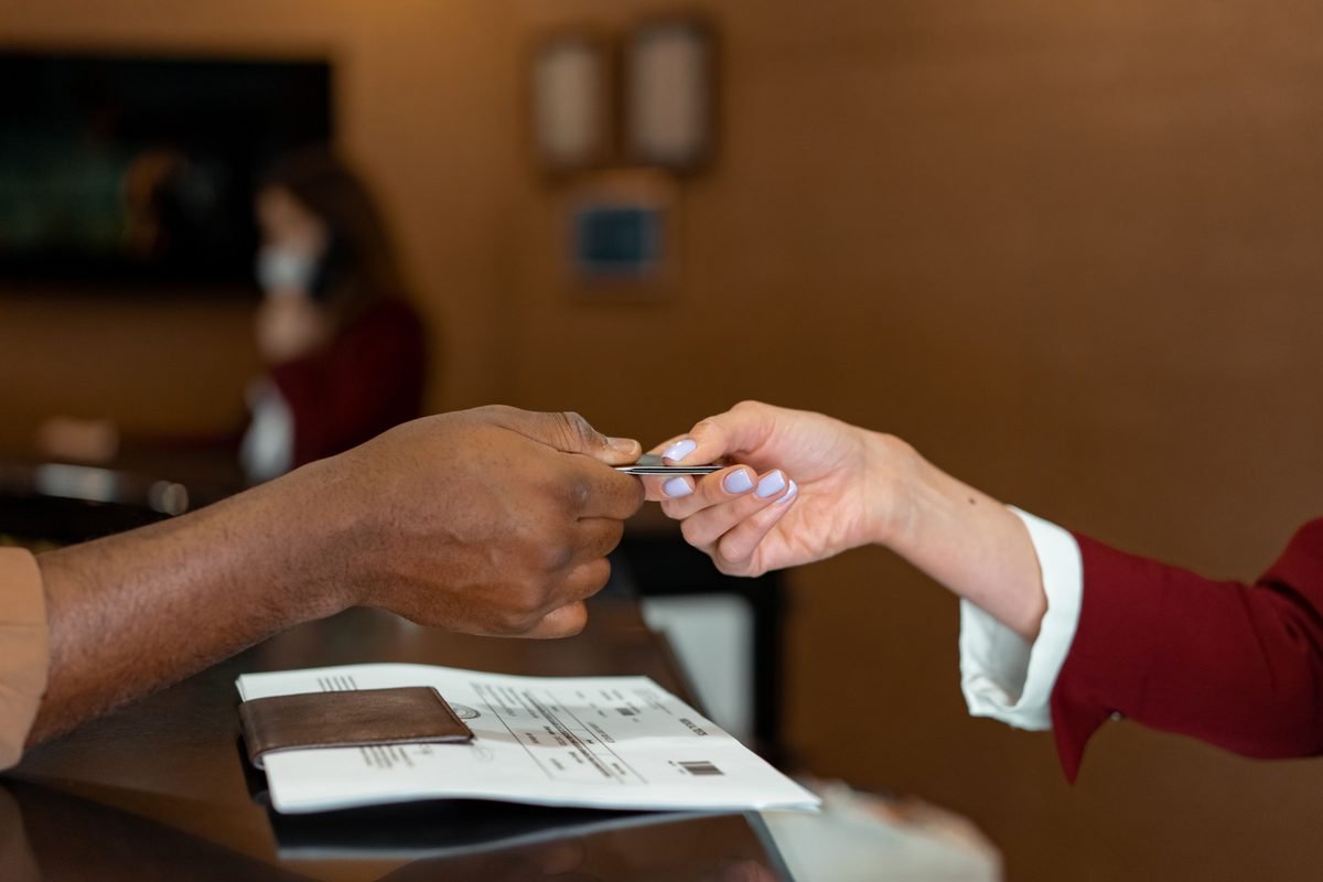 Hotel receptionist receiving a card from a guest at check-in.