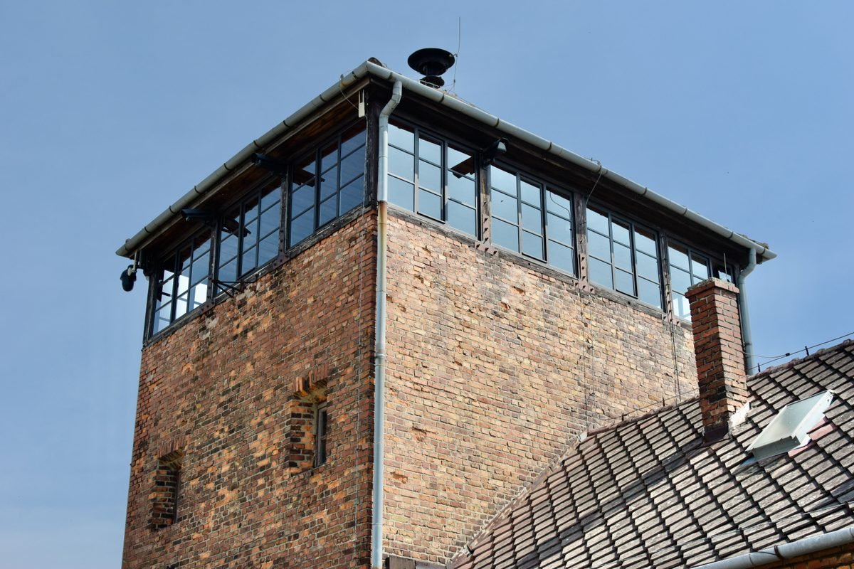 Historic brick watchtower at Auschwitz-Birkenau against a clear blue sky.