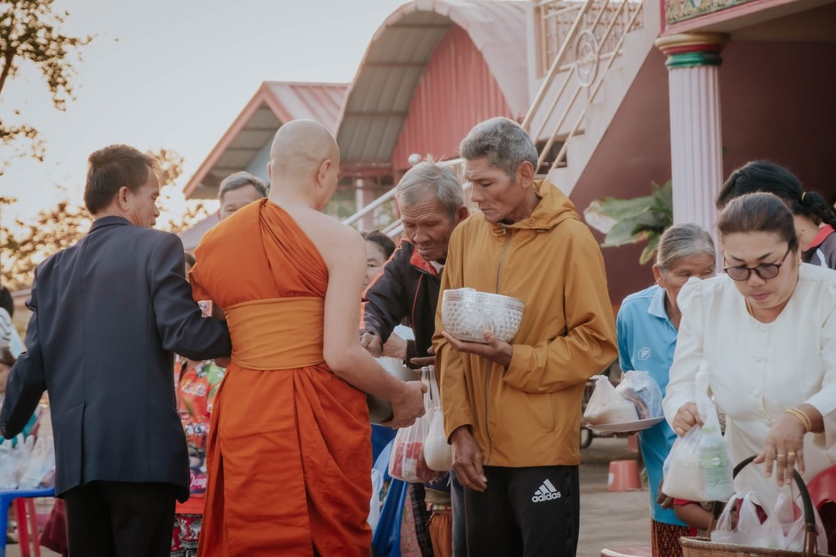 Local people giving alms to a Buddhist monk during a morning ceremony.