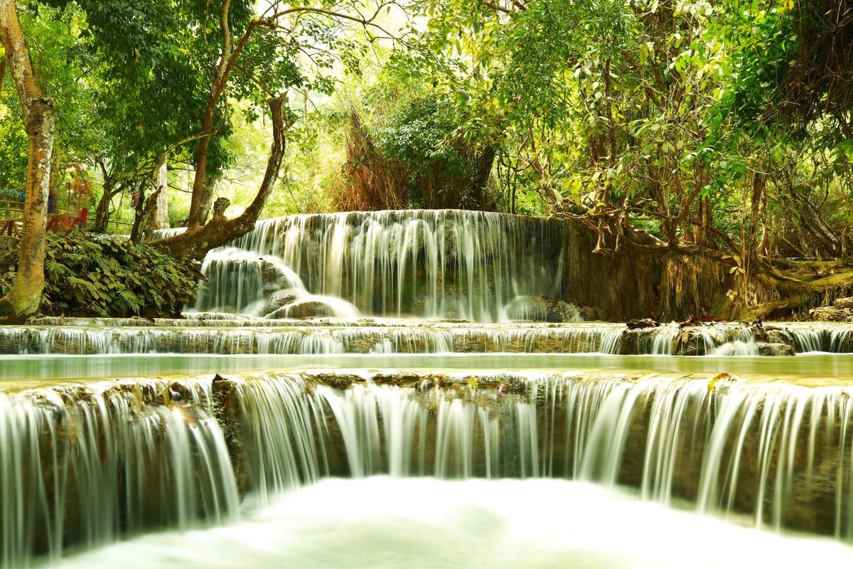 Tiered waterfall cascading through lush green jungle foliage in Luang Prabang.