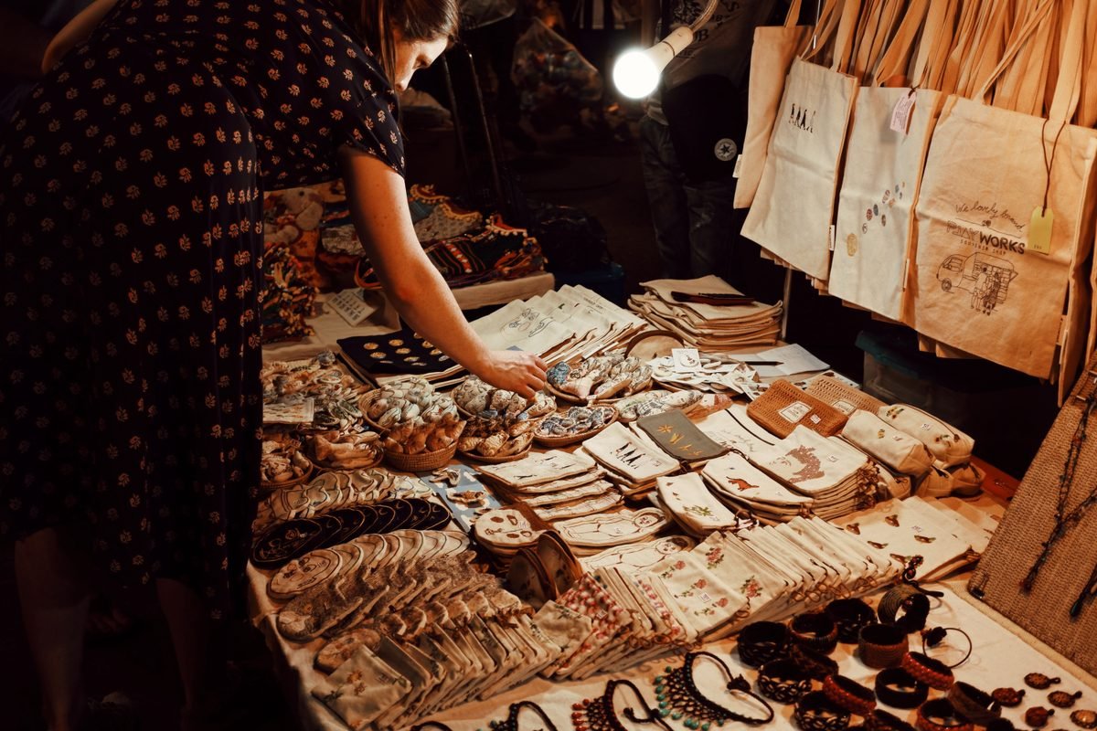Shopper browsing handmade goods at a local evening souvenir market.