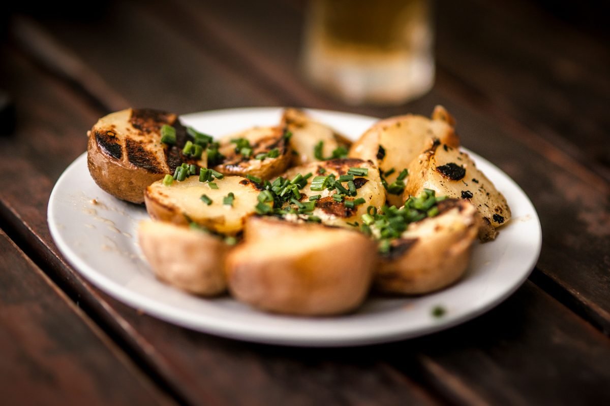 Roasted potatoes sprinkled with fresh herbs on a white plate