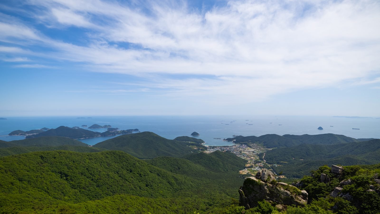 Panoramic landscape view of lush green mountains and sea islands in Namhae County.