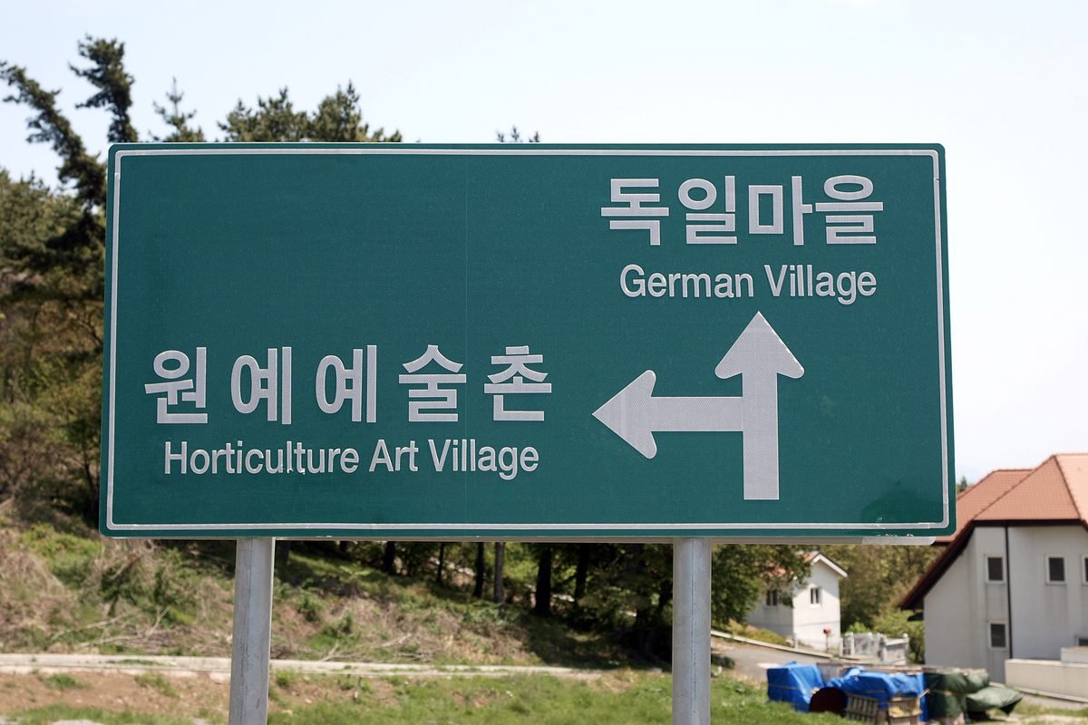 Road sign in Korean and English pointing toward German Village in Namhae