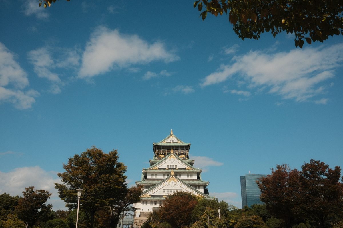 Osaka Castle framed by trees against a blue sky