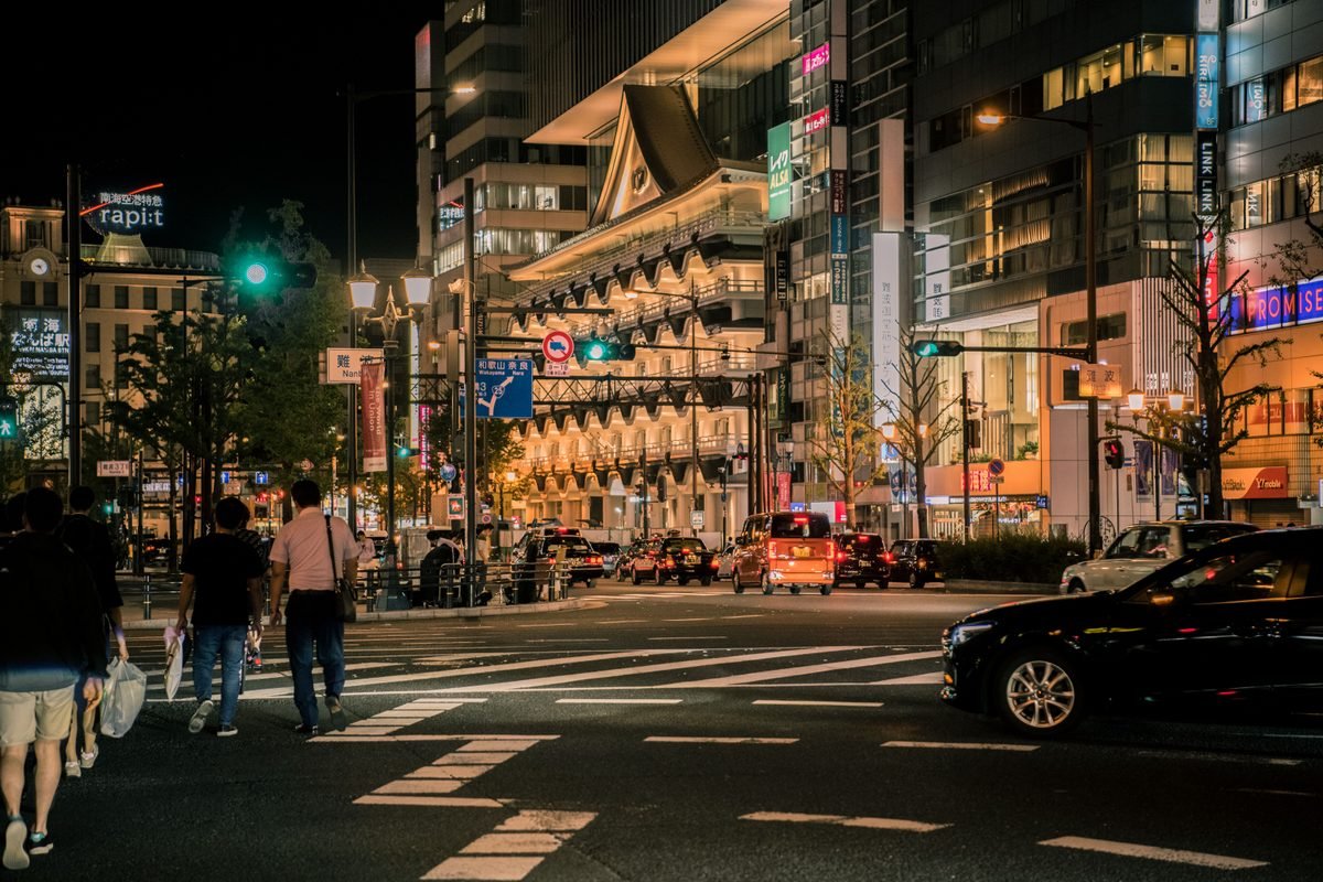 Illuminated Osaka cityscape at night with traffic and Nankai Namba station signage.