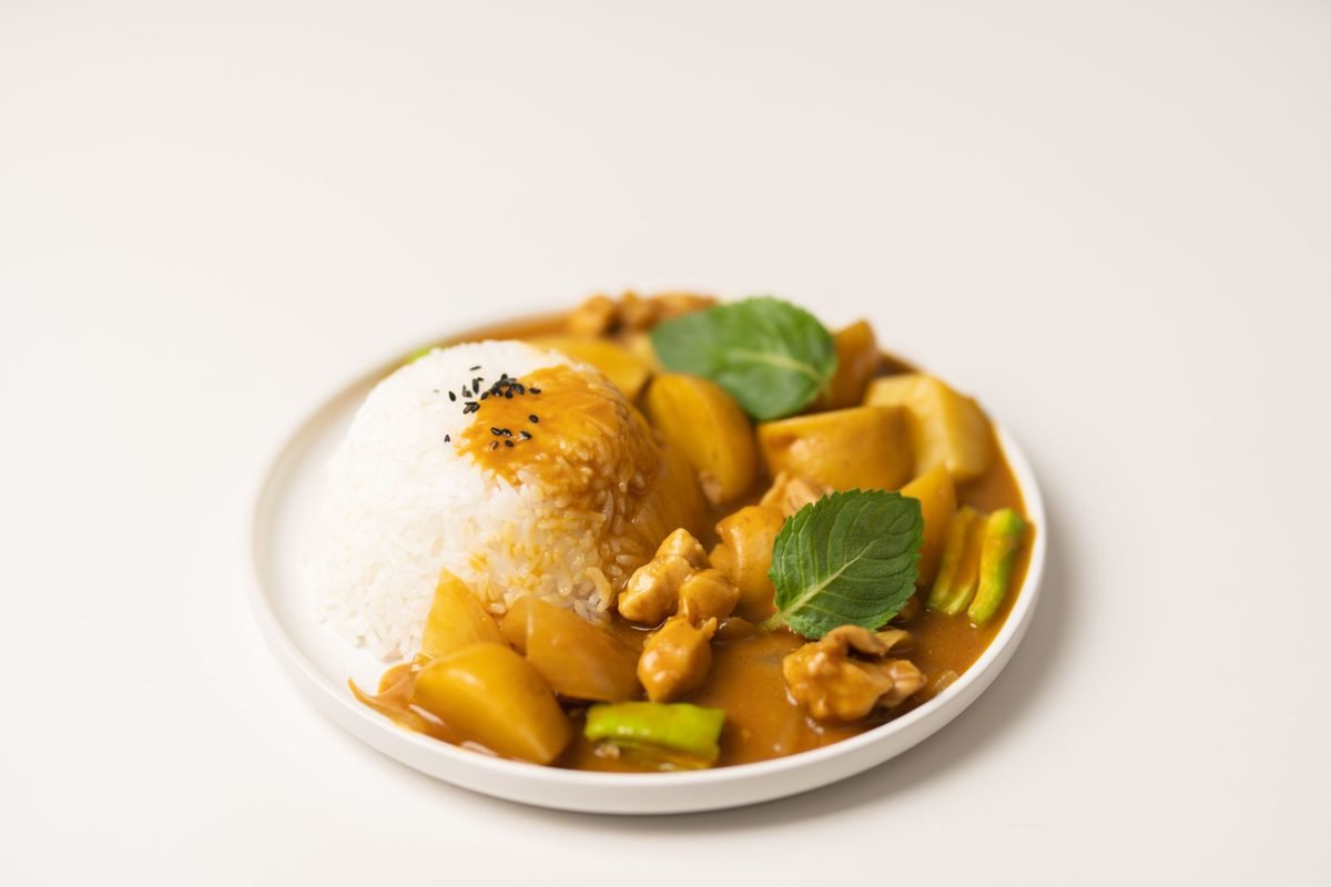 Curry stew with potatoes and meat served over white rice on a plate