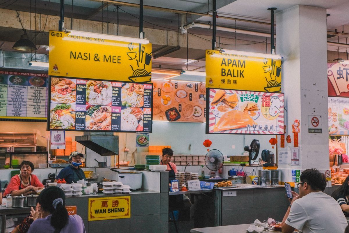 Indoor Asian food court with stalls and overhead menu boards