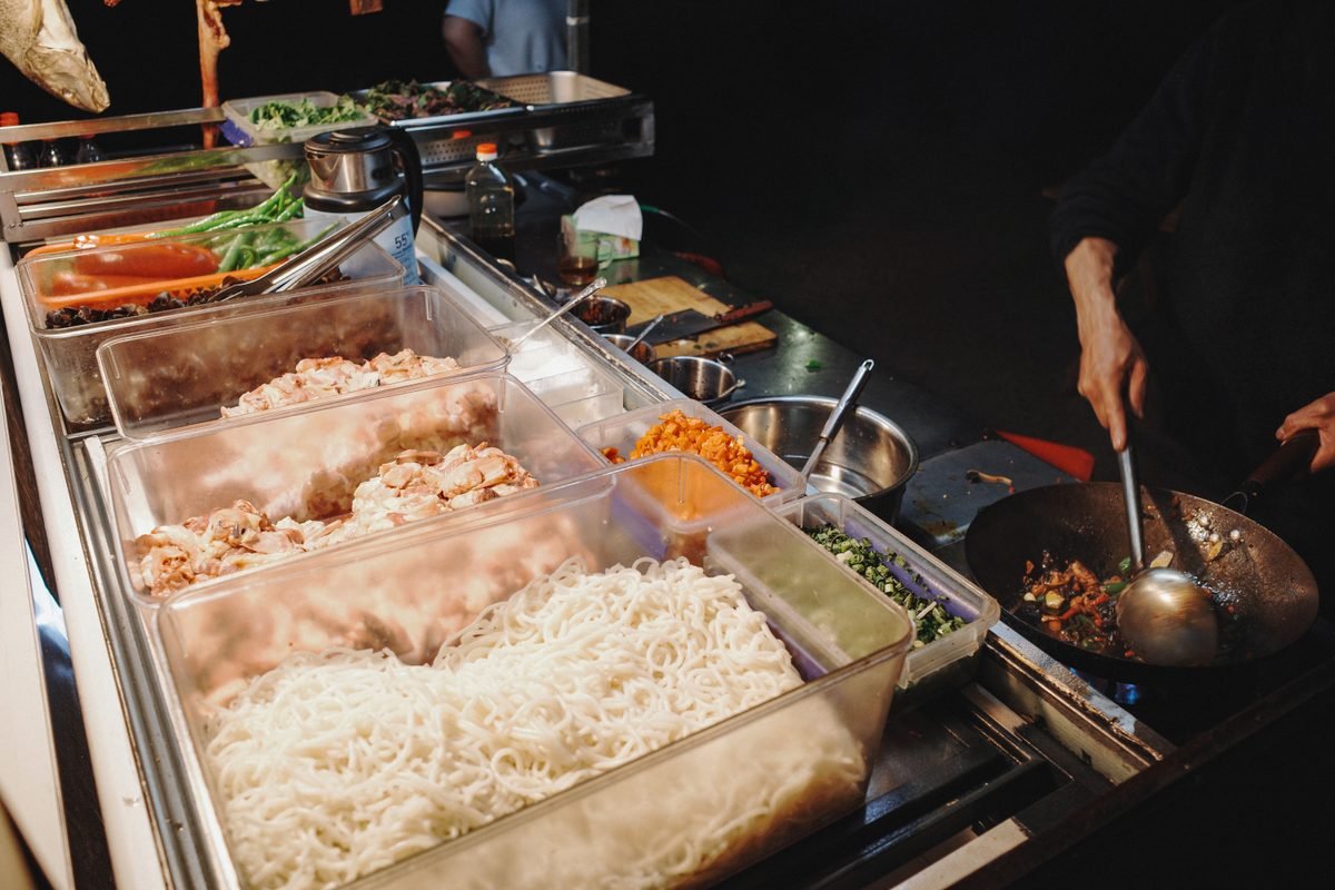 Vendor cooking noodles in a wok at a night market