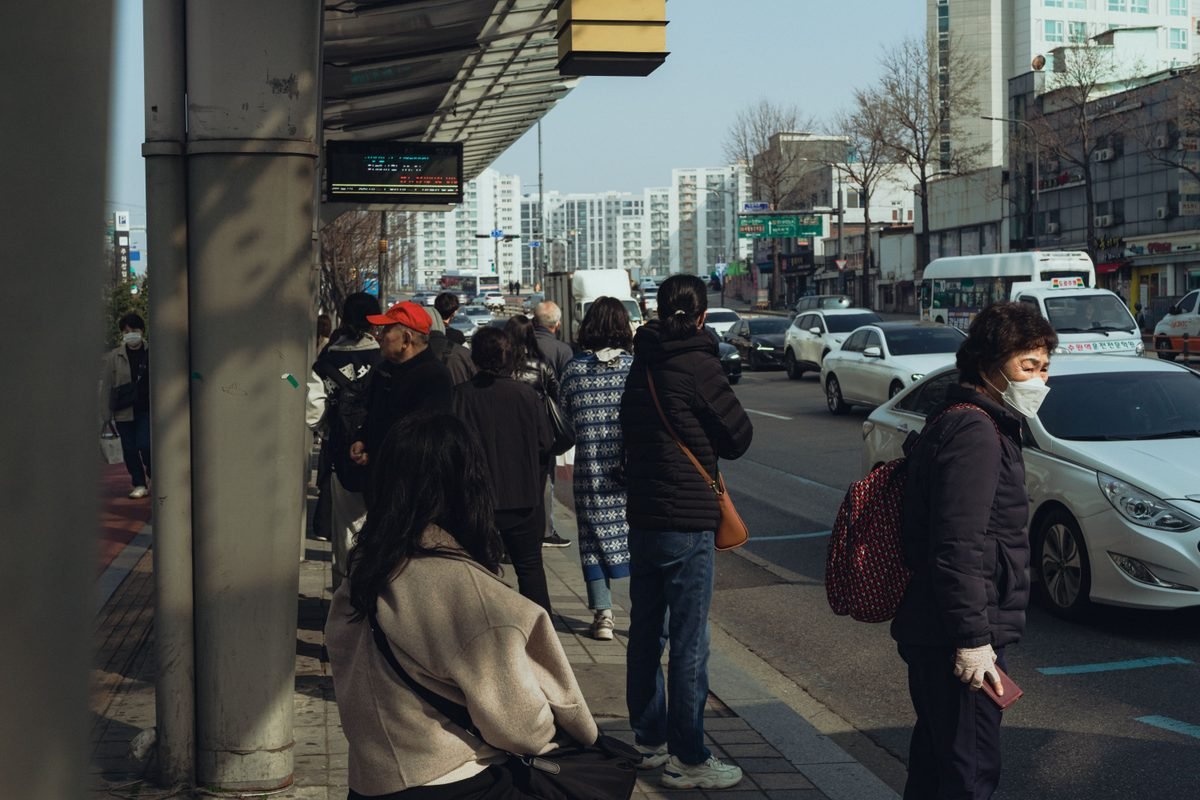 Commuters waiting at an urban bus stop during morning traffic