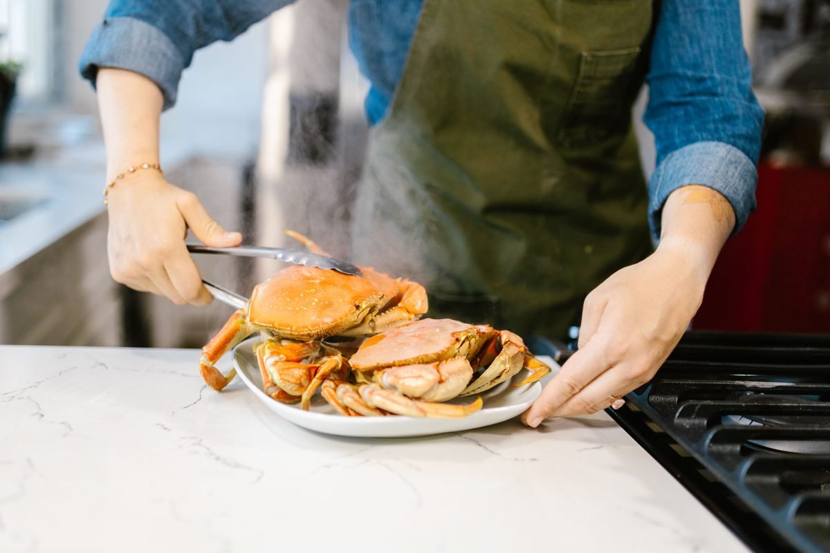 A chef cooking and serving freshly steamed crabs on a kitchen counter