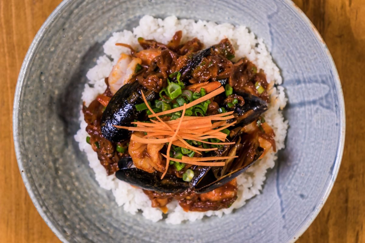 Korean seafood rice bowl garnished with vegetables and mussels
