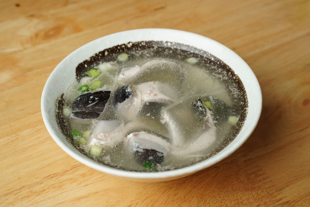 Fish soup served in a white bowl on a wooden table