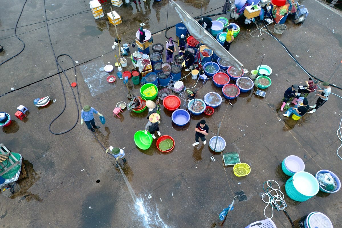 Aerial view of an outdoor market scene with colorful buckets on wet pavement