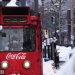 A red tram driving through a snowy street in Sapporo during a snowstorm.