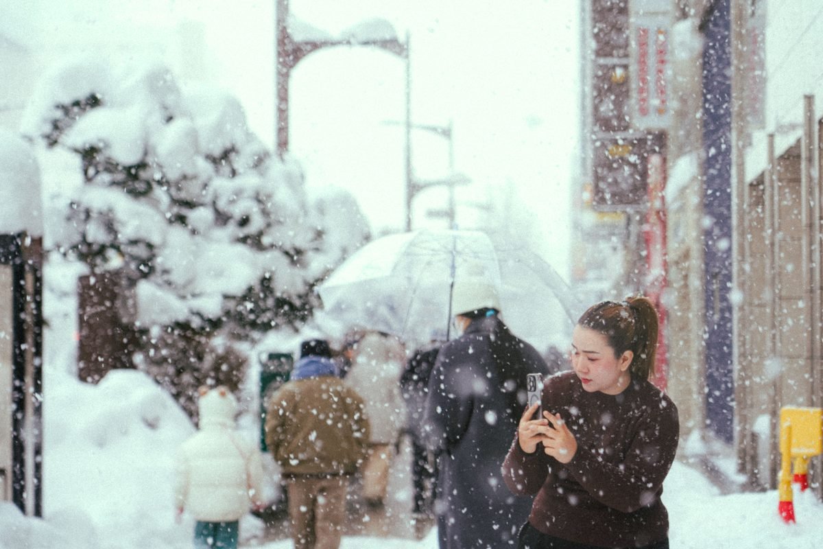 People walking on a snowy winter street while heavy snow falls.