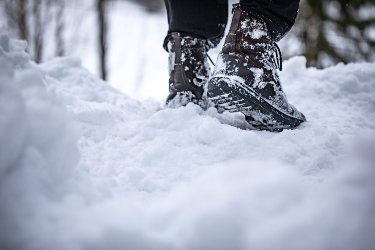 Close-up of winter boots stepping into deep snow on a snowy trail.