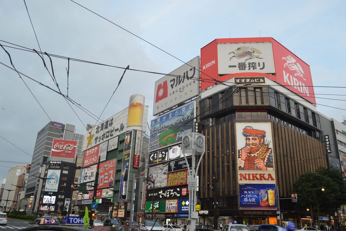 The busy Susukino intersection in Sapporo featuring large neon advertising billboards.