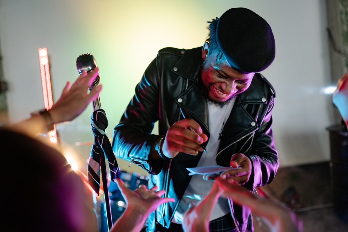 Musician in a leather jacket signing autographs for fans