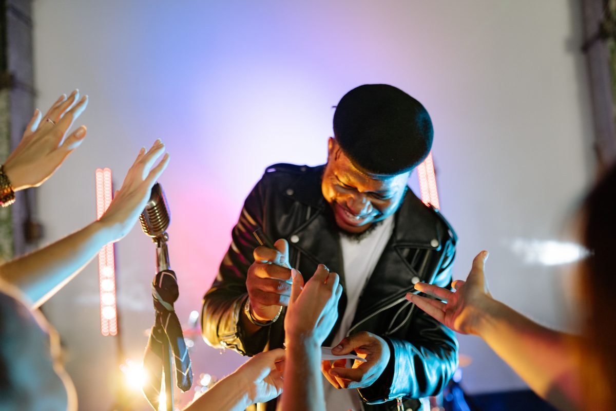 Singer signing autographs surrounded by fans' hands